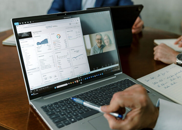 a view of a laptop screen with a client dashboard on the left and an older couple on the right, during a virtual call with the Aufman Associate team